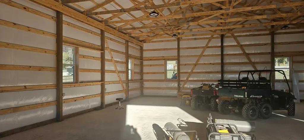 Interior of a finished pole barn with overhead lighting and a Polaris Ranger