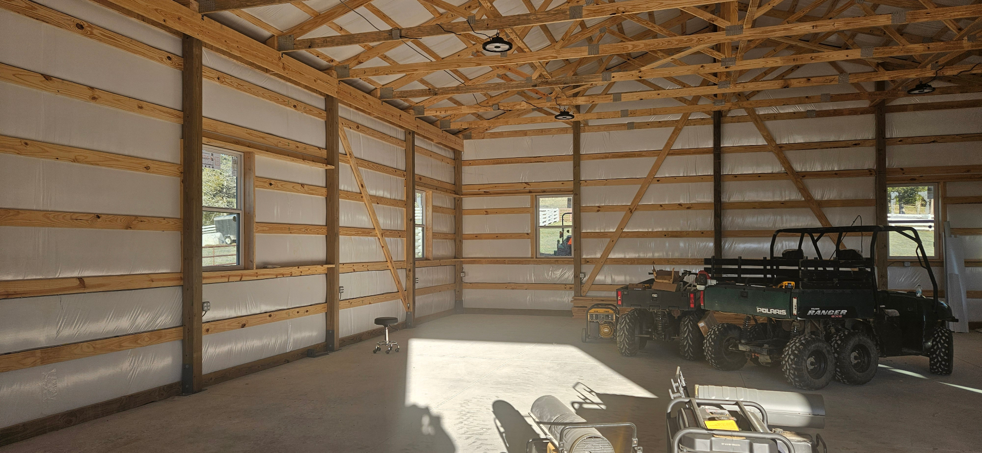 Interior of a finished pole barn with overhead lighting and a Polaris Ranger
