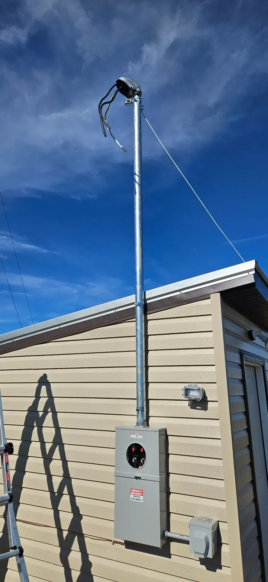 New galvanized service mast and meter base installed on the side of a home