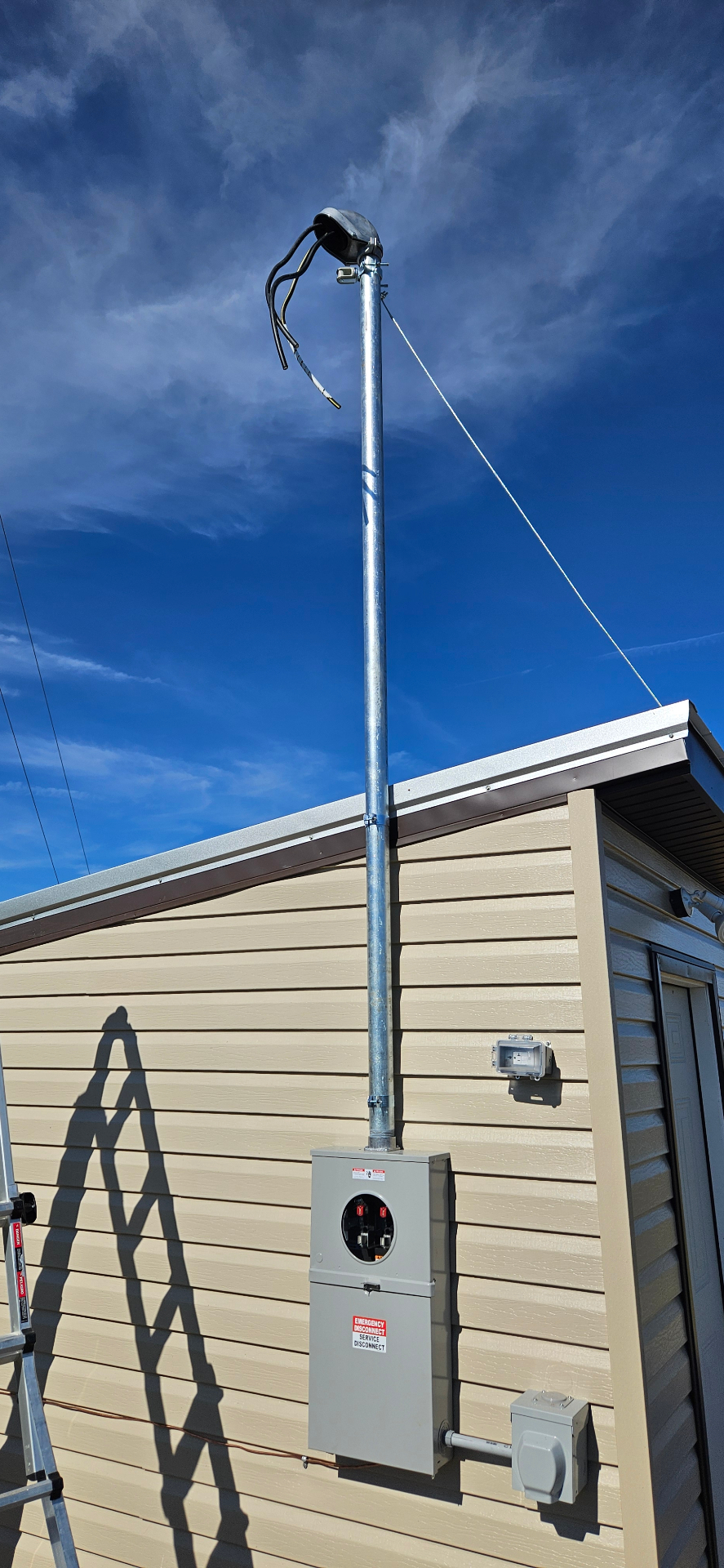 New galvanized service mast and meter base installed on the side of a home