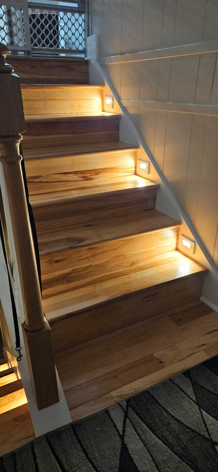 Hickory hardwood staircase with warm recessed step lights glowing on each tread
